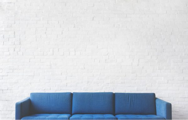 white brick wall with blue sofa in front of it